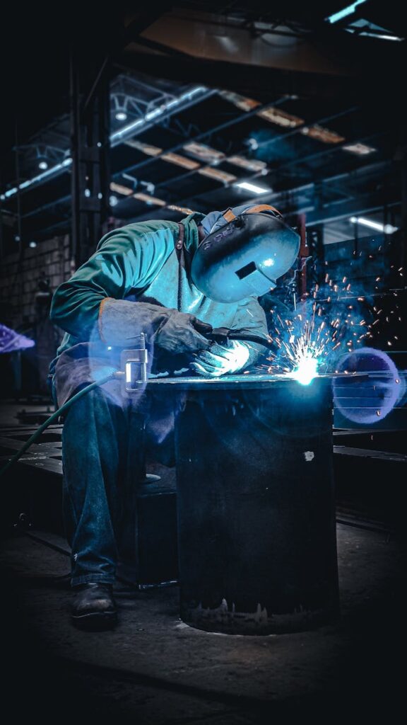 A factory worker focused on welding metal with sparks flying, showcasing industrial craftsmanship.