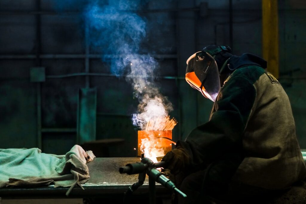 pexels-photo-3186949 Welder working in an industrial workshop with sparks and smoke.